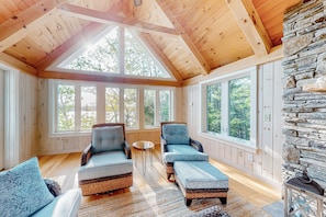 Relax in a spacious room with a high ceiling, featuring a seating area with wicker sofas and a stone accent wall.