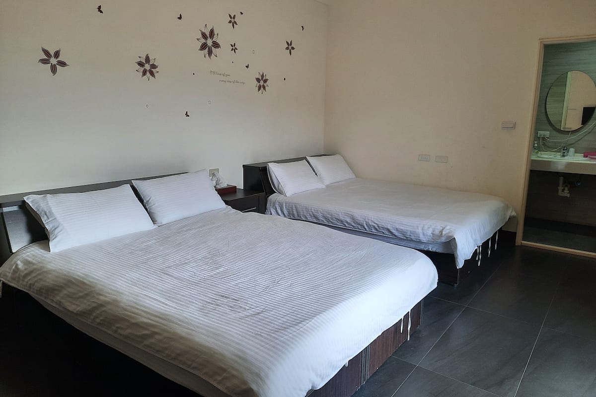 Een hotelkamer met twee bedden, een spiegel en een wand met bloemdecoraties.
