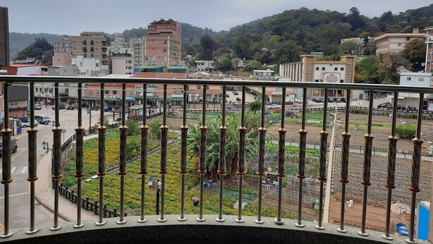 A balcony with a view of a cityscape, including buildings and a hillside. - Jiu Wu Xiao Zhu (Nangan)