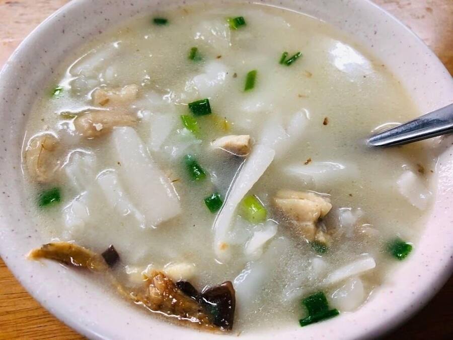 A bowl of soup with noodles and green onions.