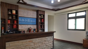 A reception area with a stone wall, wooden shelves, and a blue sign. - Jiu Wu Xiao Zhu (Nangan)