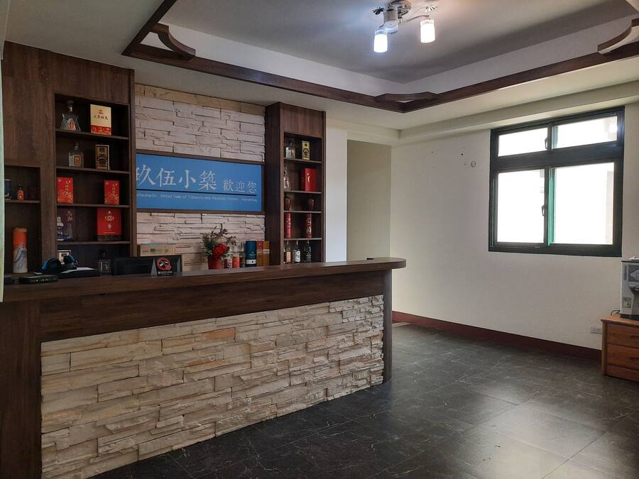 Un área de recepción con pared de piedra, estantes de madera y un letrero azul.