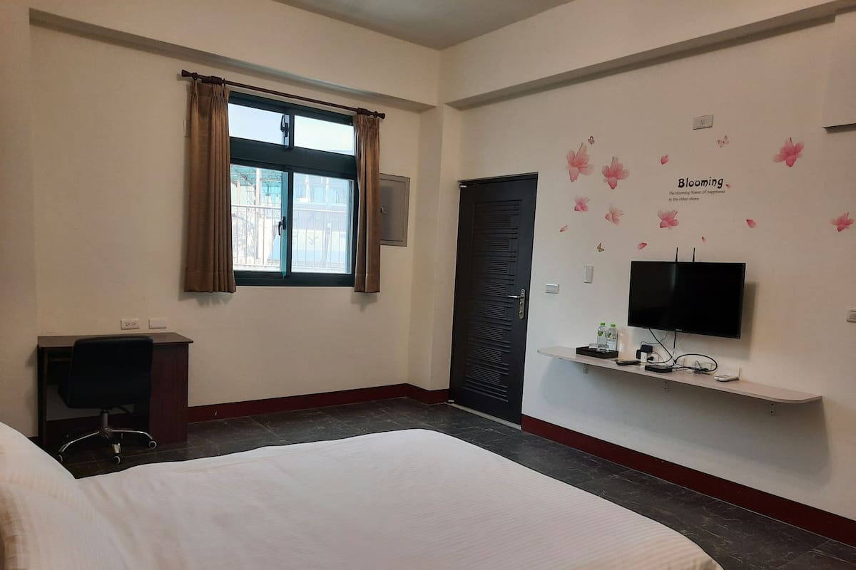 Een hotelkamer met een bed, een bureau, een televisie en een raam met gordijnen.