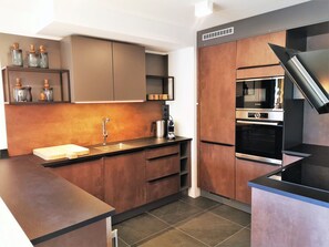 Een moderne keuken met een inbouwoven, een koffiezetapparaat en een spoelbak.