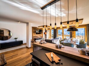 A modern kitchen with a wooden island, hanging pendant lights, and a view of a snowy landscape. - Cozy duplex, 8 ppl, parking, Les Gets (Les Gets)