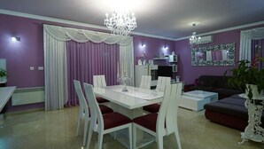 A modern living room with a dining area, featuring a chandelier, purple walls, and a large mirror. - Villa Daniela (Solin)