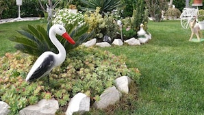 A garden with a swan statue, various plants, and a white horse statue. - Villa Daniela (Solin)