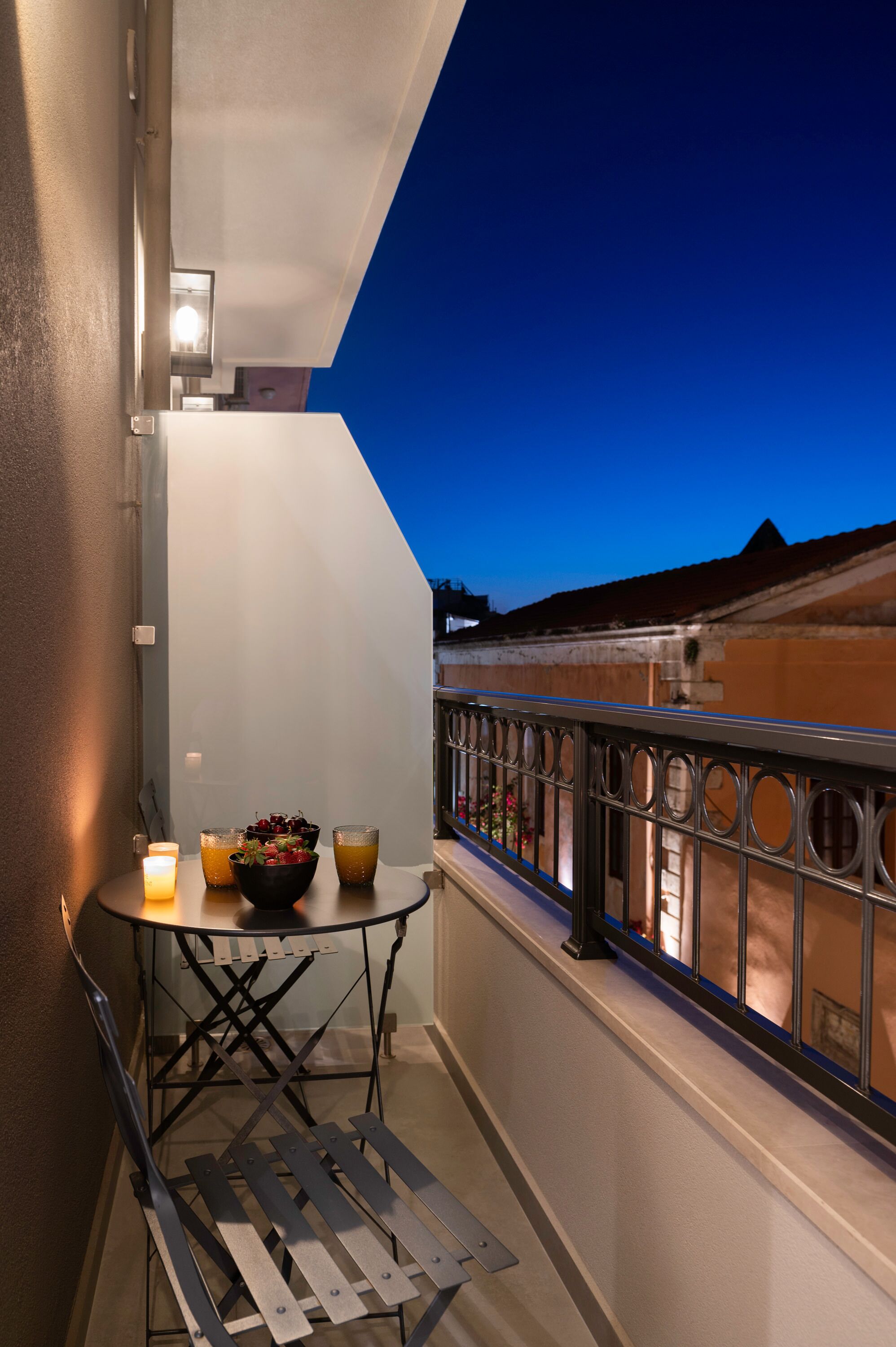 A balcony with a table, candles, and a bowl of fruit.