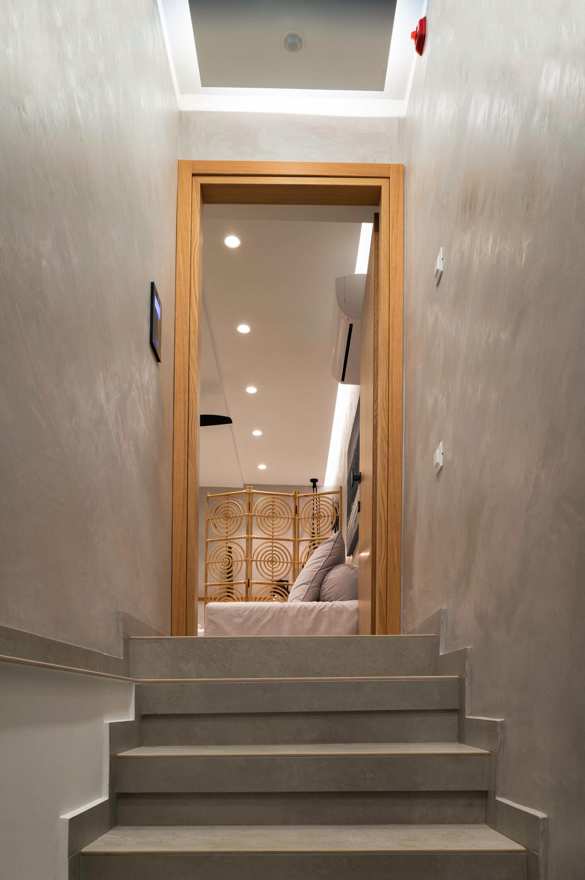 A staircase leading to a bedroom with a bed, a wooden door frame, and a ceiling light.