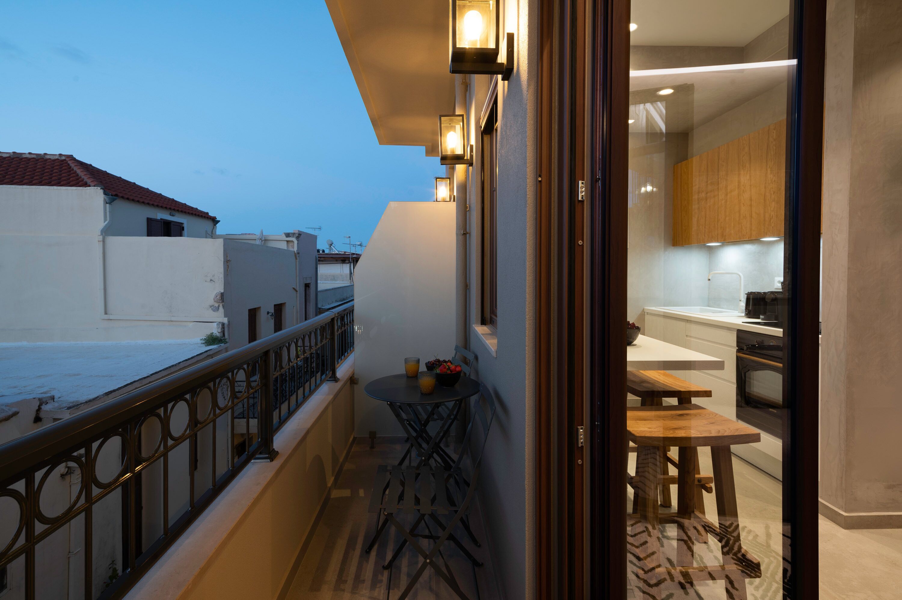 Un balcón con mesa y sillas, una pequeña cocina equipada con microondas y vistas a los edificios circundantes.