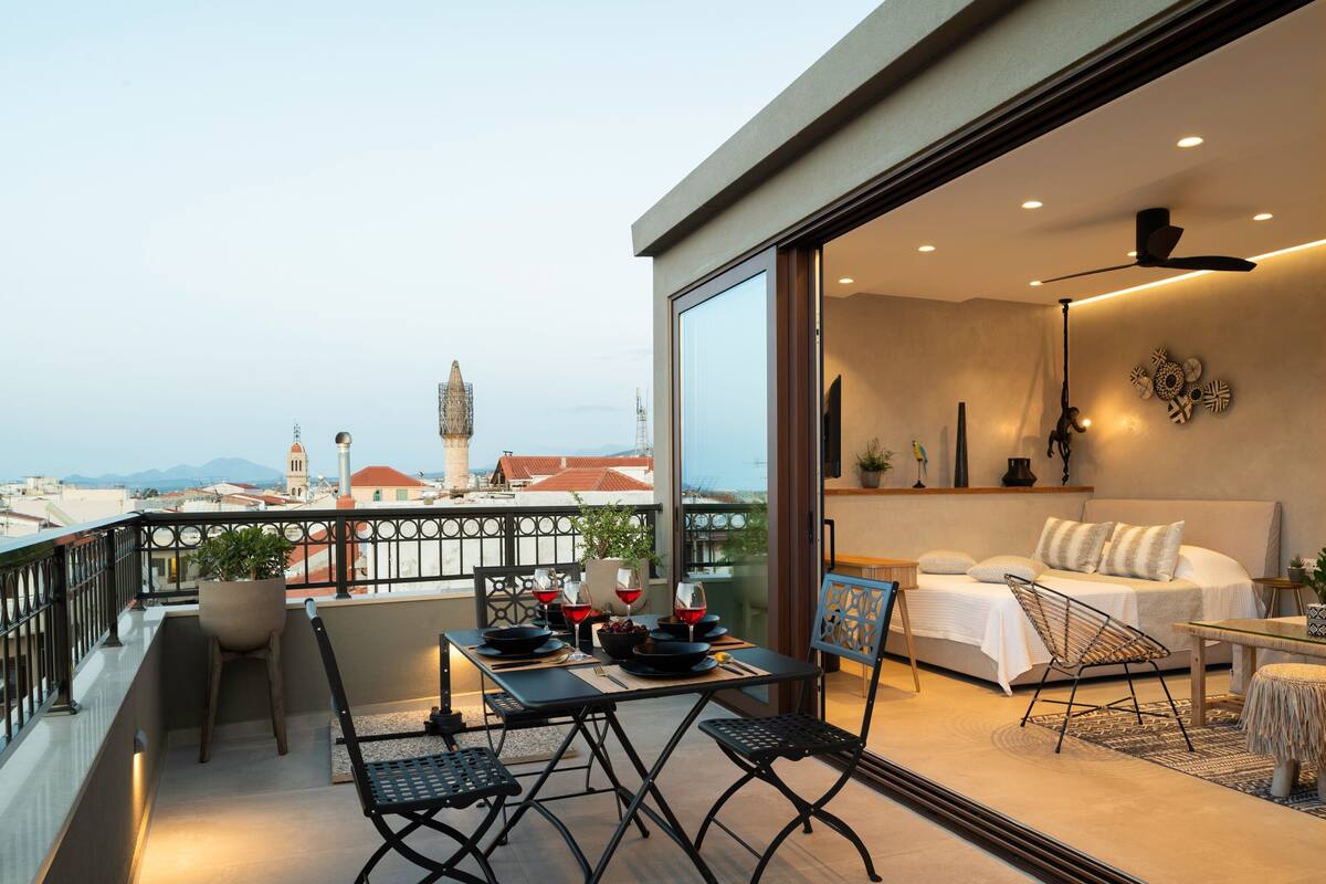 A balcony with a dining table, chairs, and a view of the cityscape.