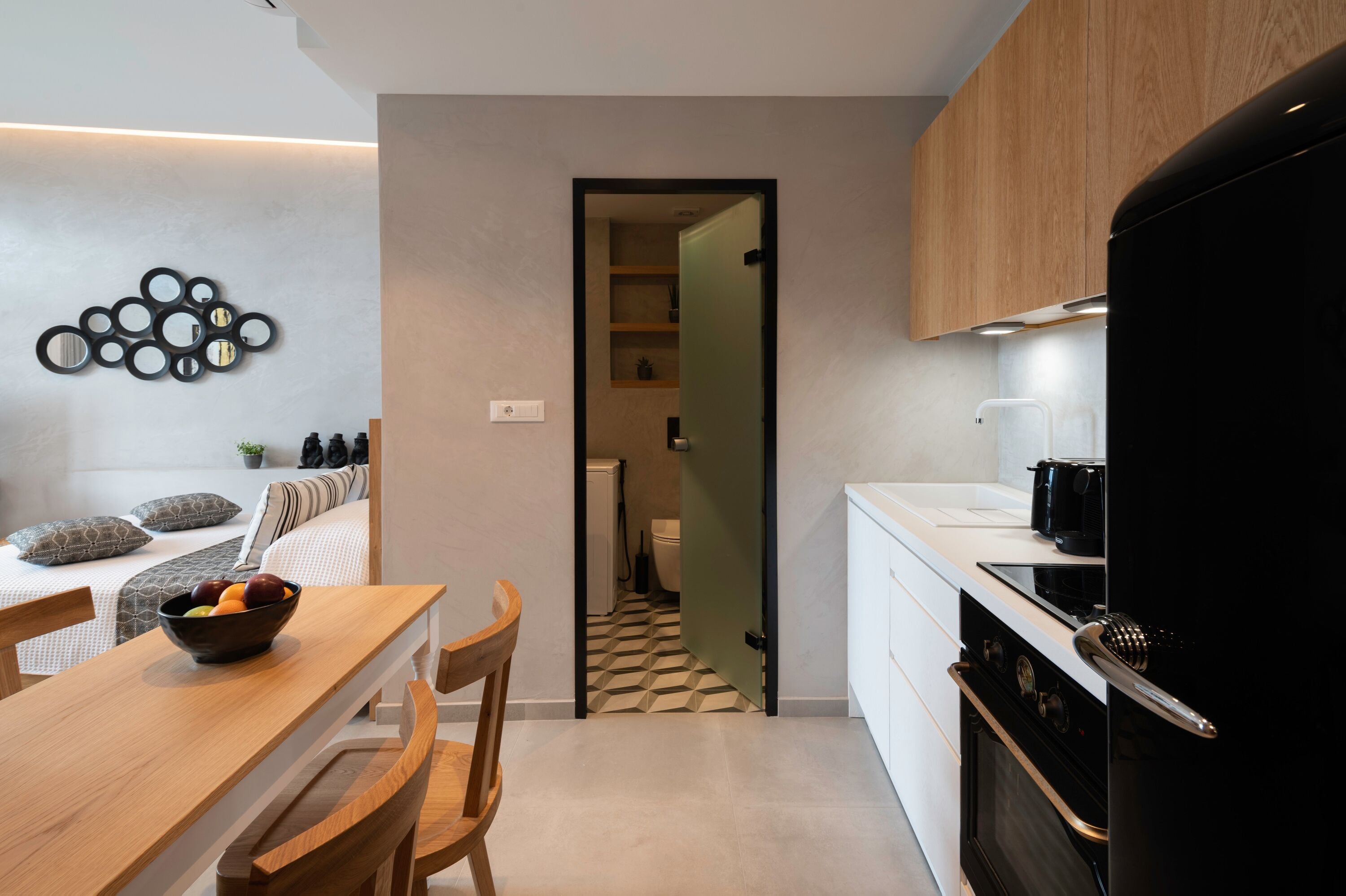 A modern kitchen with a wooden cabinet, a black refrigerator, and a white countertop.