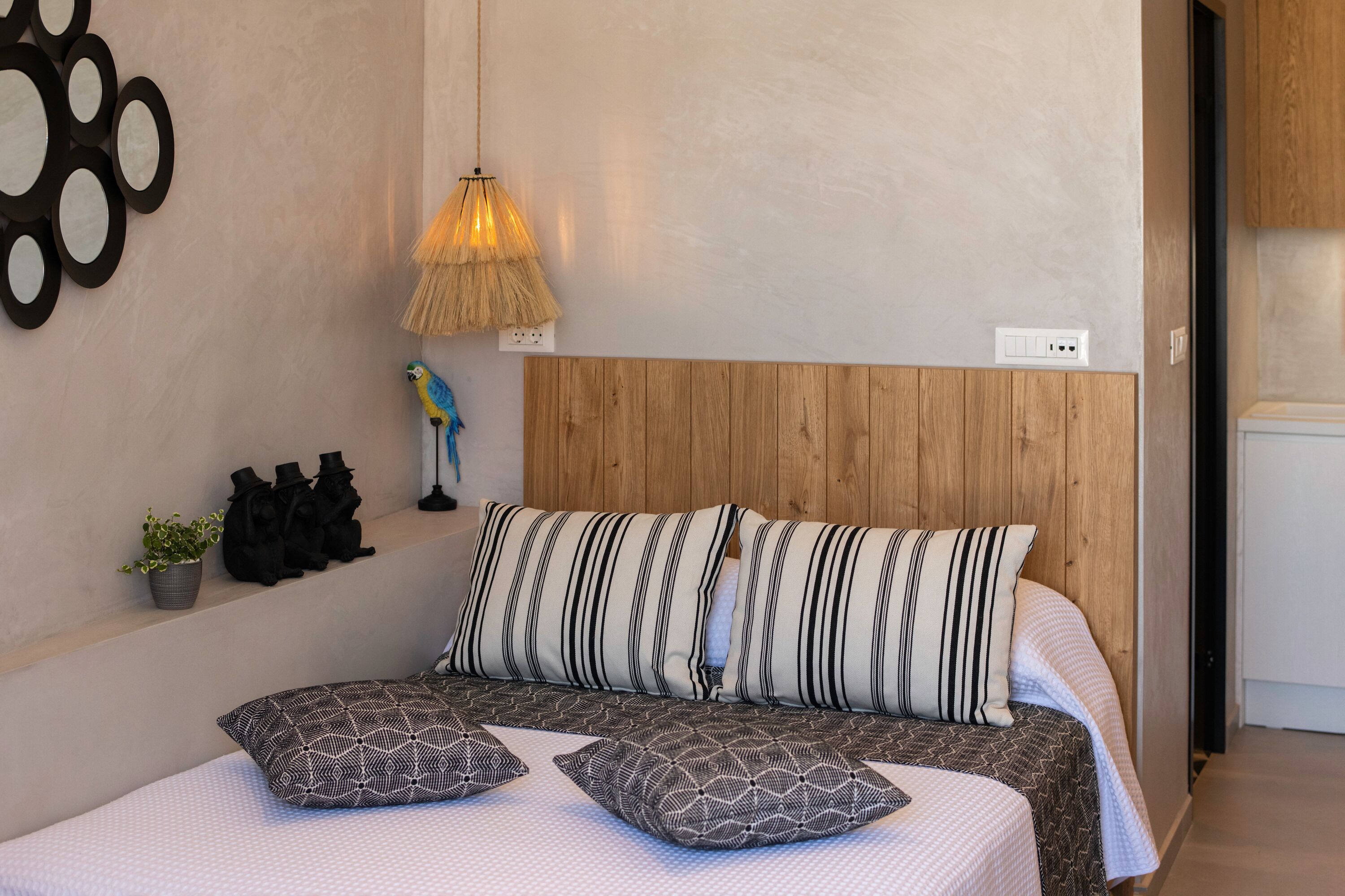 Ein Schlafzimmer mit einem hölzernen Kopfteil, gestreiften Kissen und einer gemusterten Bettdecke.