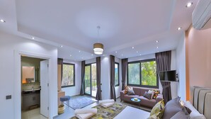 Une chambre d’hôtel moderne dotée d’un grand lit, d’un canapé, d’une télévision et d’un balcon offrant une vue sur la verdure.