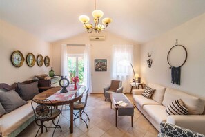 Uma sala de estar acolhedora com um sofá, uma mesa de jantar e um candelabro.