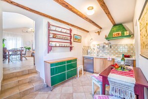 Uma cozinha com um armário verde, uma mesa de jantar de madeira e uma escada que leva a outro quarto.