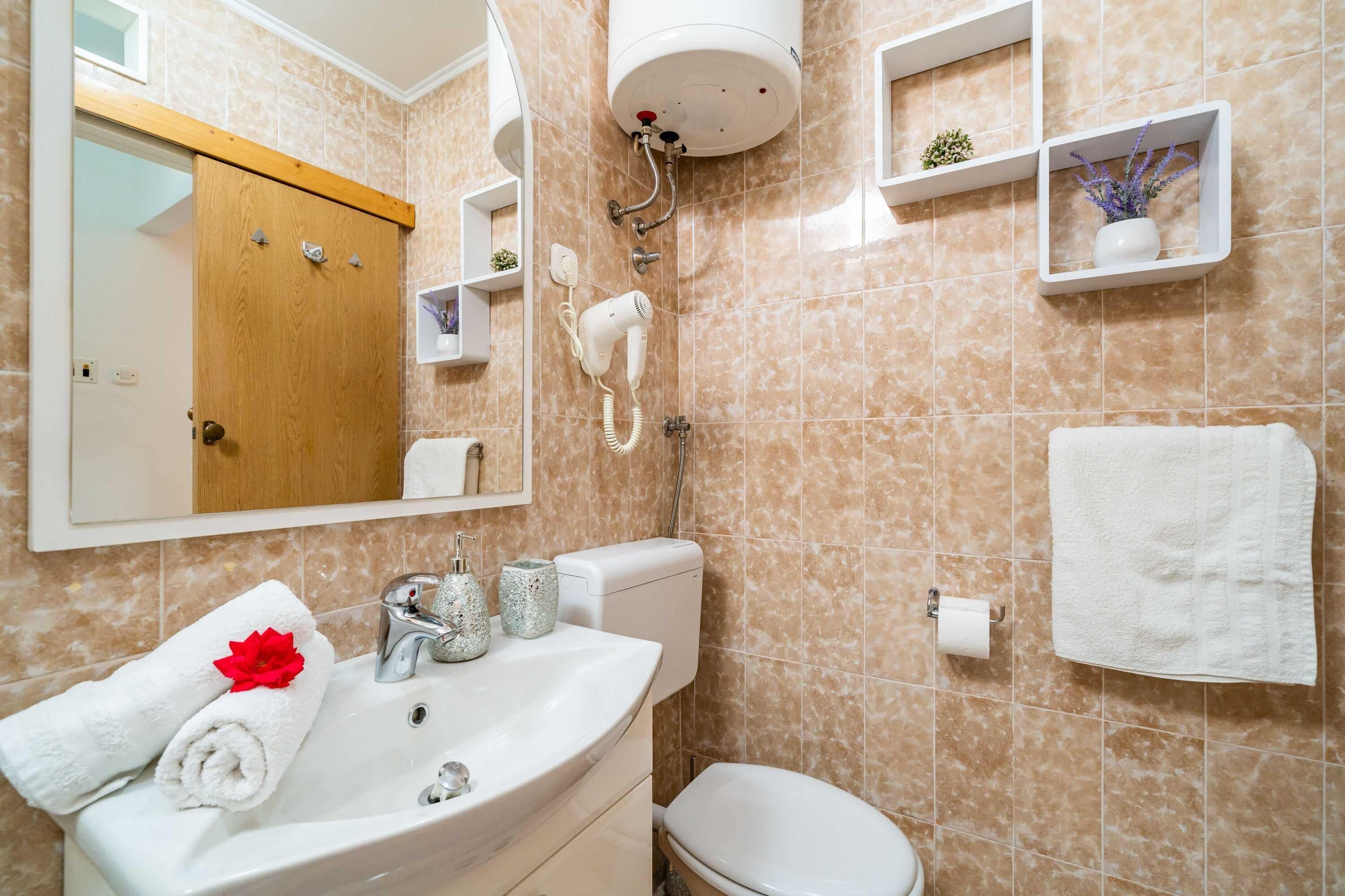 Une salle de bain équipée d’un lavabo, de toilettes et d’une douche avec un sèche-cheveux portatif.