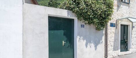 Un bâtiment avec une porte verte, un mur en pierre et une enseigne indiquant le numéro de la pièce : 22.