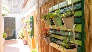 Una cerca de madera con varios maceteros colgantes con diversas flores y plantas.