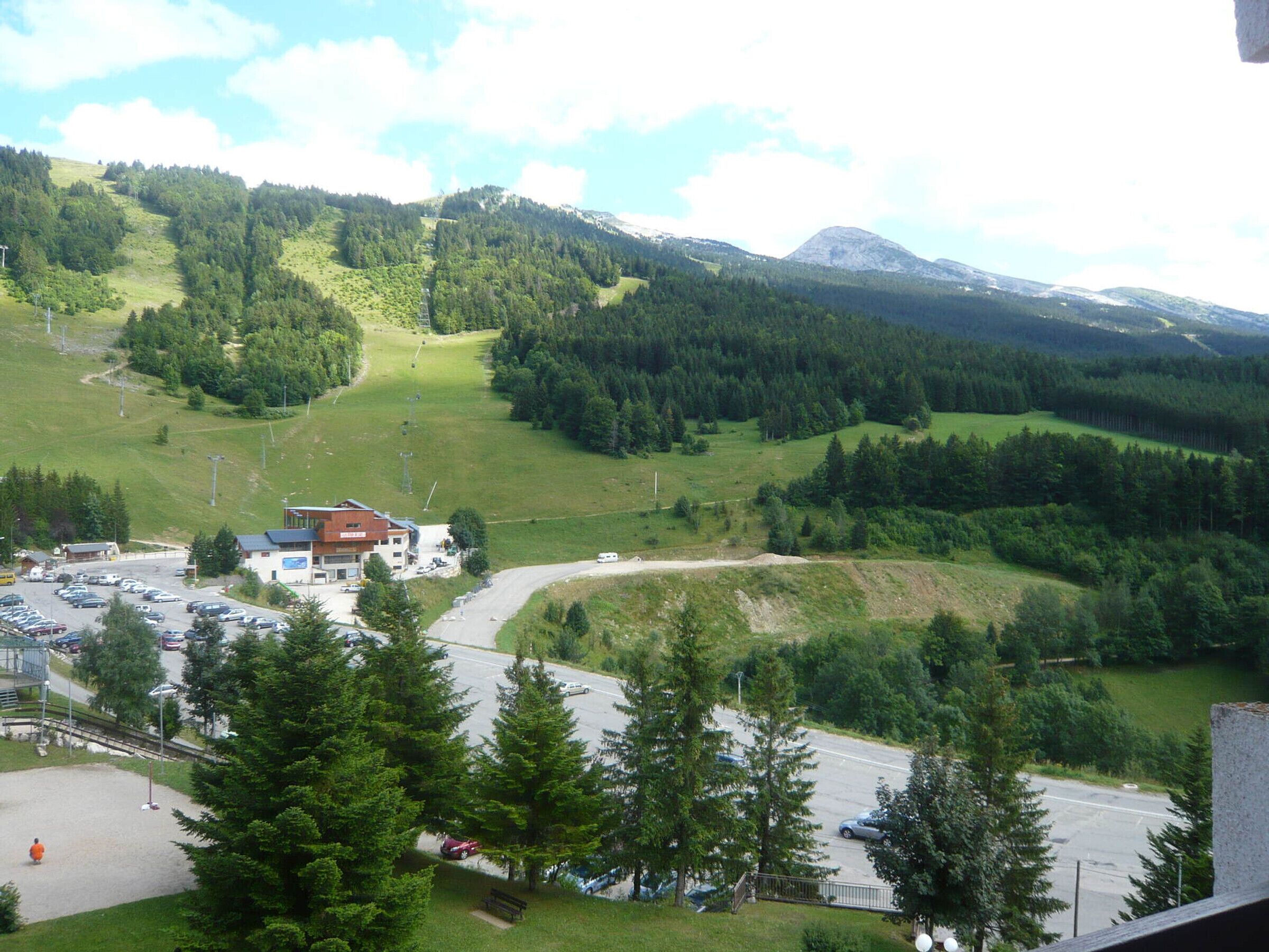 A mountainous landscape with a parking area and a building with a sign.