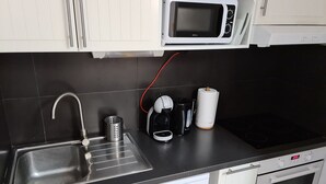 A kitchen with a microwave, coffee maker, kettle, and a dishwasher.