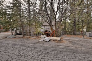 A residential area with a paved driveway, a wooden deck, and a house with a visible front porch. - Falling Leaves by Destination Big Bear : Premiere Moonridge Cabin Offering a Perfect Setting for Escaping to the Mountains! (Big Bear Lake)