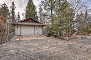 A garage with a wooden roof, a white garage door, and a small porch area with a railing. - Falling Leaves by Destination Big Bear : Premiere Moonridge Cabin Offering a Perfect Setting for Escaping to the Mountains! (Big Bear Lake)