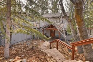 A wooden staircase leading to a house with a porch, surrounded by trees and a fence. - Falling Leaves by Destination Big Bear : Premiere Moonridge Cabin Offering a Perfect Setting for Escaping to the Mountains! (Big Bear Lake)