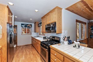Una cocina con armarios de madera, electrodomésticos de acero inoxidable y salpicadero de azulejos.