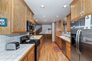 Eine moderne Küche mit Holzausstattung, Edelstahlgeräten und einer gefliesten Spritzschutzwand.