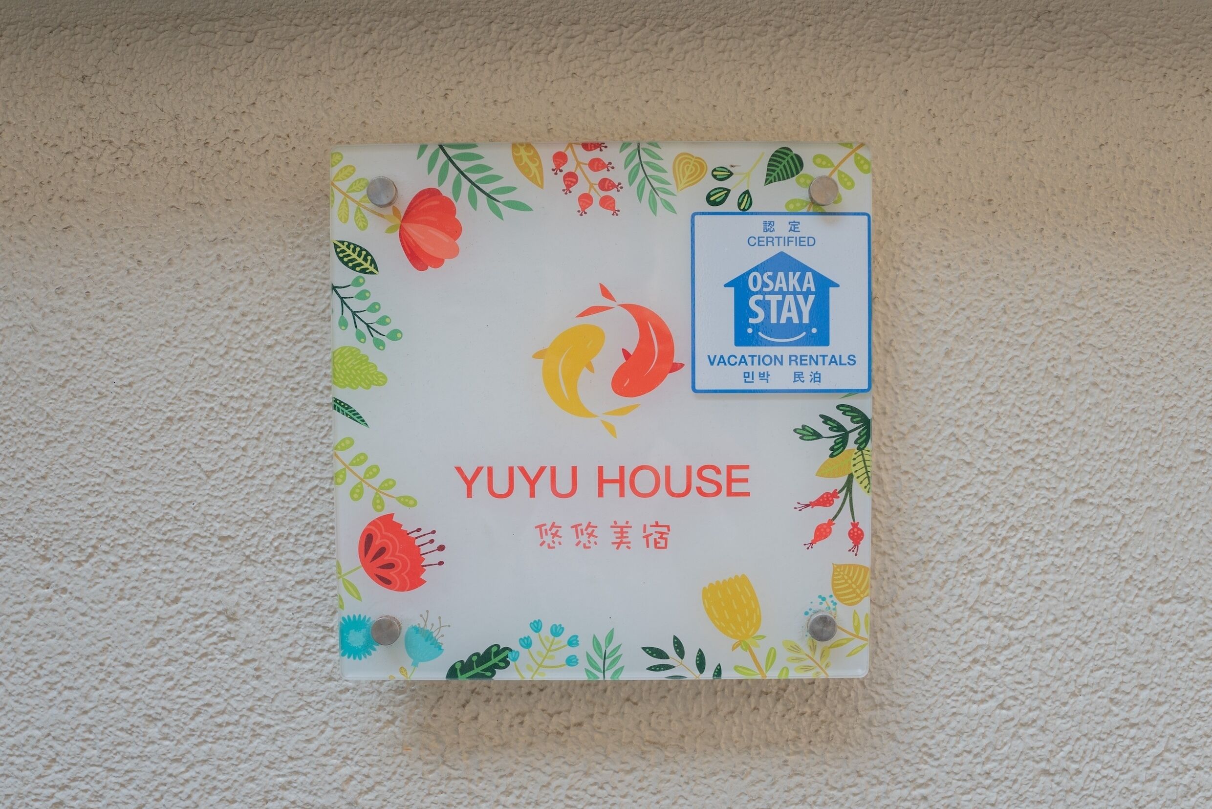 Segnaletica per Yuju House, affitto turistico certificato con un design floreale colorato.