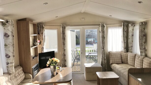 A cozy living area with a sofa, a table with a vase of flowers, and a television.