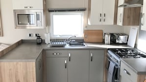 A compact kitchen with a microwave, toaster, sink, and stove.