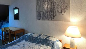 A bedroom with a bed, a desk, a chair, a lamp, and a wall art piece. - Charming Duplex at the Foot of Corrençon Slopes (Corrençon-en-Vercors)