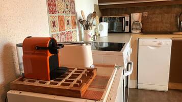 Une cuisine compacte équipée d’un grille-pain, d’un four à micro-ondes, d’une machine à café et d’un lave-vaisselle.