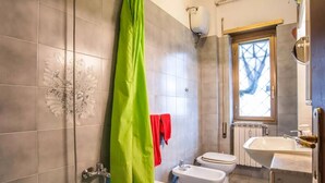 A bathroom with a bathtub, two bidets, a toilet, and a sink.