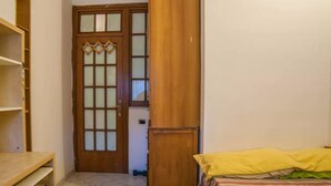 A room with a bed, a wooden wardrobe, and a door with frosted glass panels.