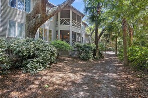 A house with a covered porch, a pathway leading to the entrance, and surrounding greenery.