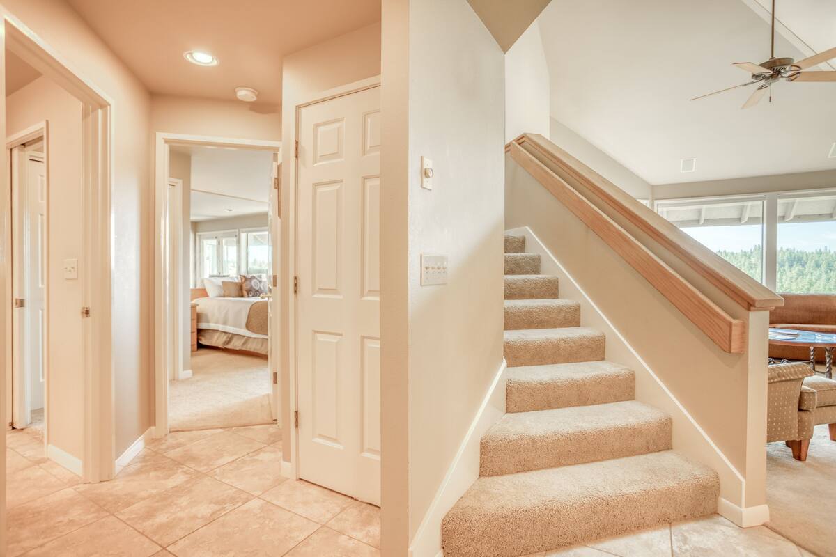 A spacious hallway with carpeted stairs leading to a bedroom with a large window.