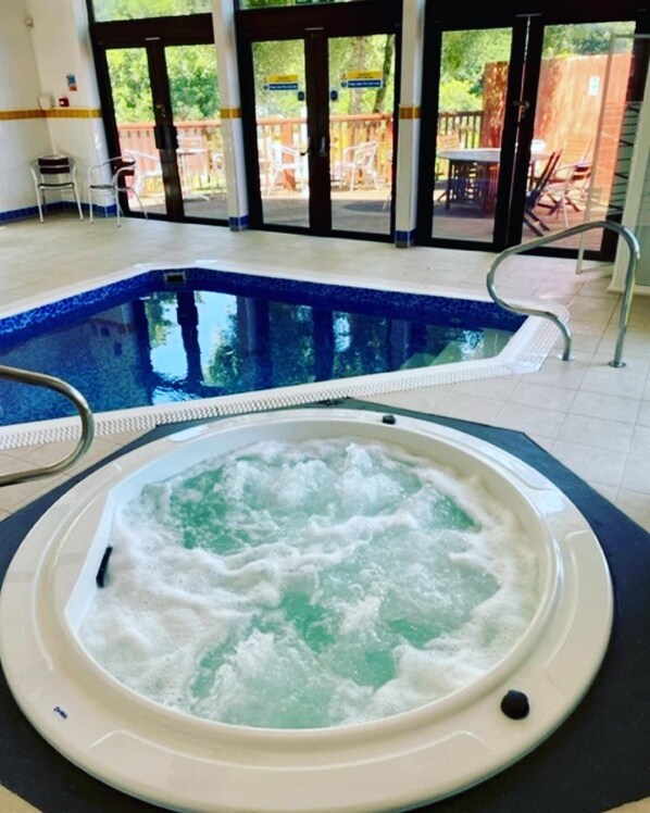 A hot tub with a pool in the background.