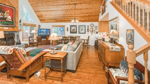 A spacious living room with a wooden ceiling, a sofa, a wooden coffee table, and a staircase. - BlackDog Hideaway_Hot Tub, (2) Arcades, Foosball, PingPong, Smart Tv's, Cable + HOA Amenity Passes (Truckee)