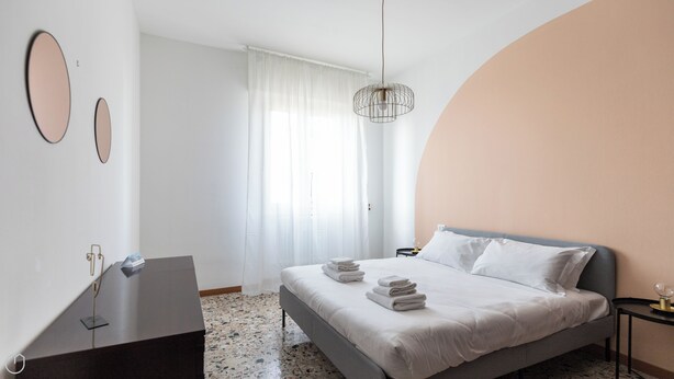 Quarto moderno com cama, escrivaninha e janela com cortinas.