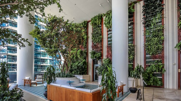 Un hall d’entrée moderne avec un comptoir d’accueil en bois, un espace salon et des jardins verticaux.