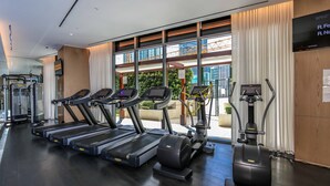 Une salle de sport équipée de tapis de course, de vélos elliptiques et d'appareils de musculation.