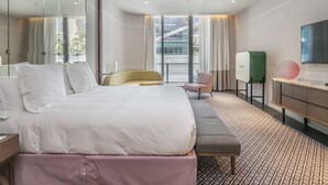 Une chambre d’hôtel moderne avec un grand lit, un banc, un bureau et une télévision.
