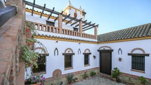 A courtyard with a white building, arched windows, and a tiled roof. - Holiday Home ‘La Cazuela’ with Mountain View, Pool, Garden & Terraces (Arcos de la Frontera)