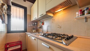 Een keuken met een gasfornuis, kastjes, een raam en een rode krat.