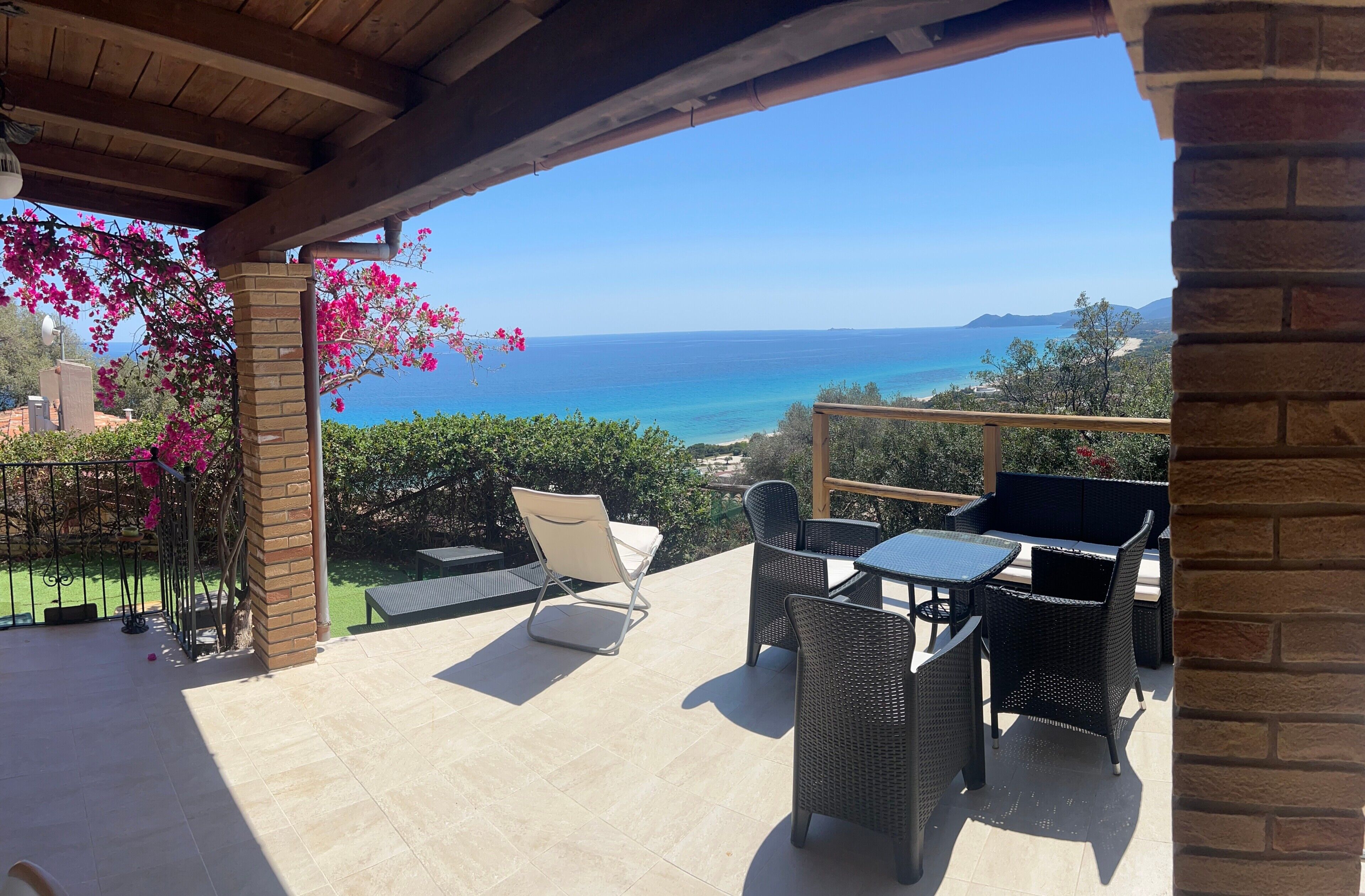 Une terrasse avec des meubles d’extérieur, une vue sur la mer et un mur en briques.