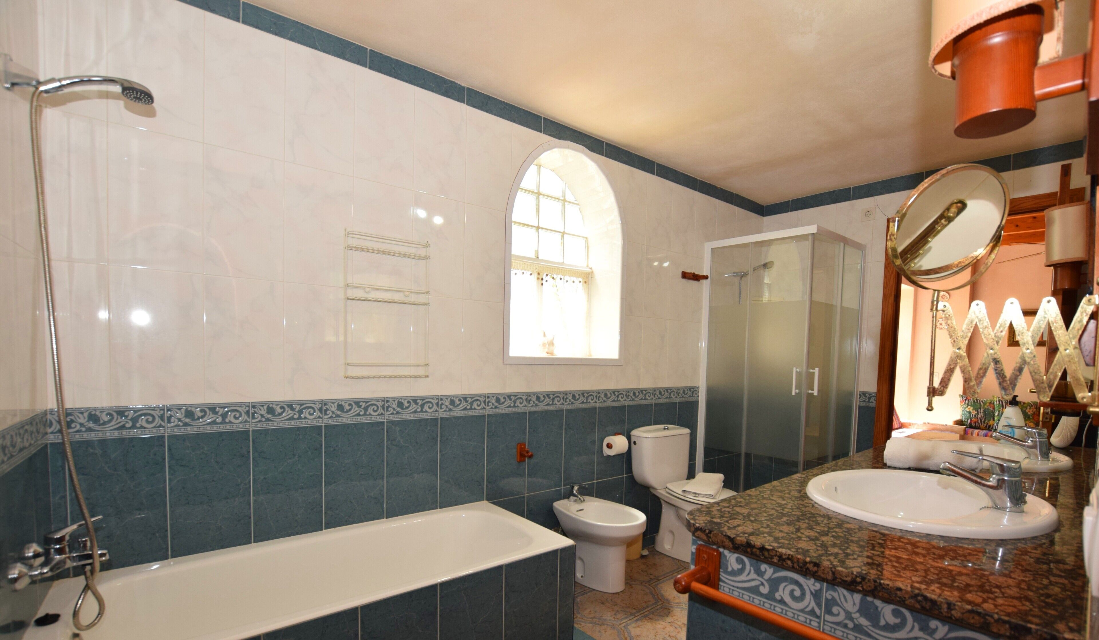 Een badkamer met een badkuip, toilet, bidet en een douchecabine met glazen wanden.