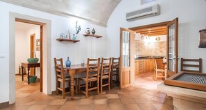 Un comedor con mesa y sillas de madera, una cocina con armarios de madera y un suelo de baldosas.